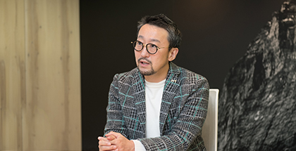 グレーのジャケットを羽織って真面目に話す男性