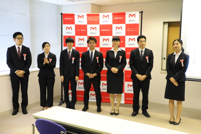 弾幕の前に緊張して並ぶスーツを着た男女