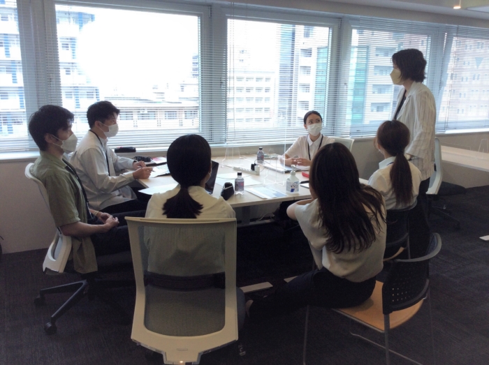 学生と社員が一緒に机を囲み話し合いをしている
