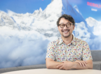 花がらのシャツで微笑むメガネの男性