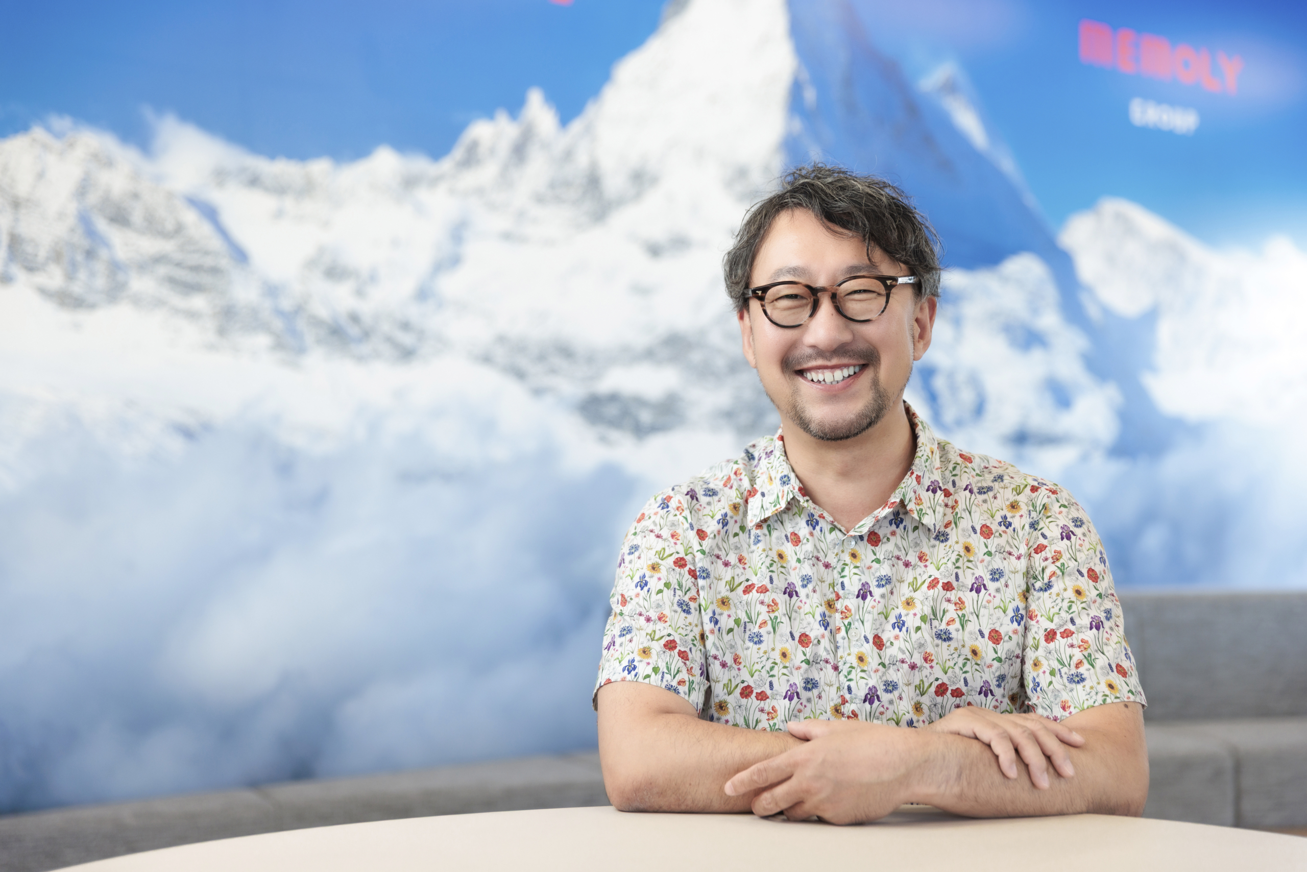 花がらのシャツで微笑むメガネの男性