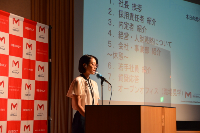 スポットライトを浴び、堂々と話す司会者