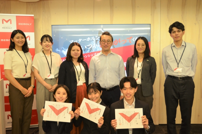 表彰所を掲げている学生と社員の集合写真