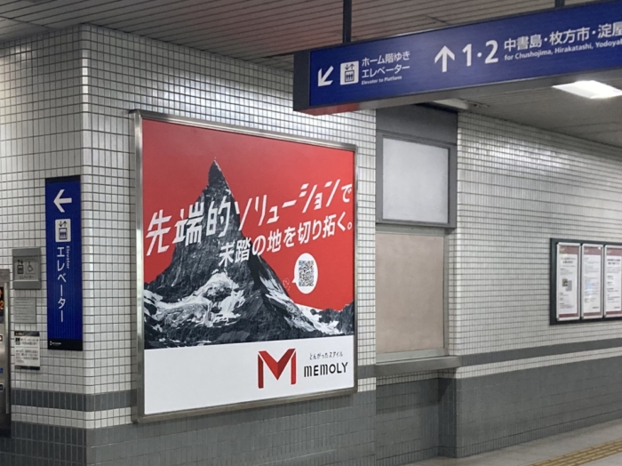 駅構内の通路に設置されている赤い背景にマッターホルンが描かれている壁面広告