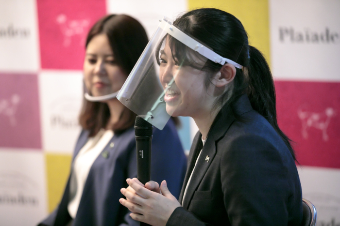 フェイスガードを装着し、マイクで語る女性