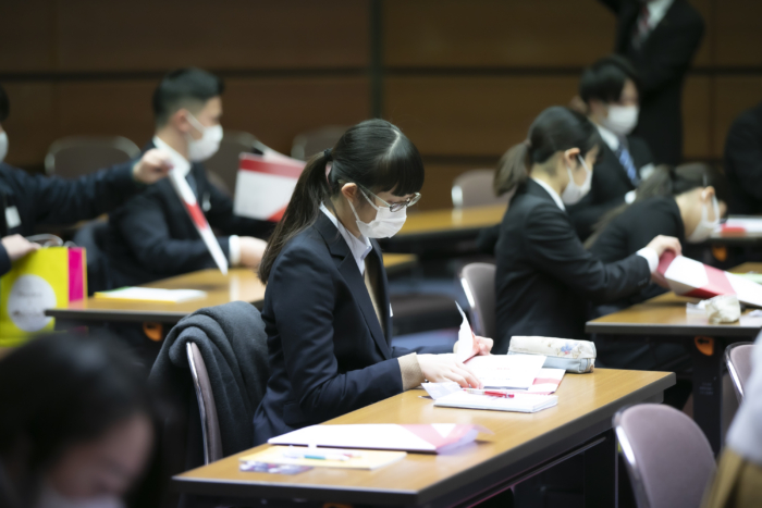 パンフレットを見つめる大勢の学生