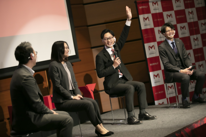 手を上げるメガネの男性とほほ笑む社員